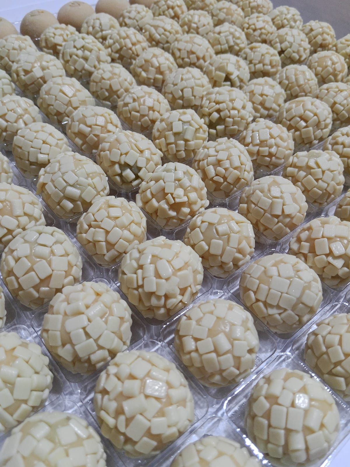 Brigadeiros brancos com confeitos de chocolate branco